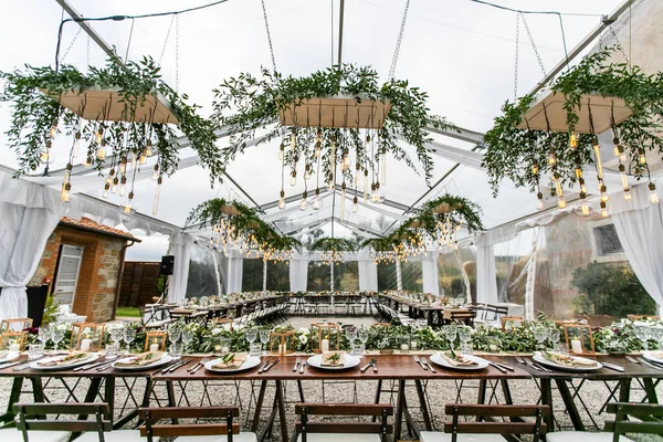 Toskana 'daki villanın arka bahçesinde pamuk ve okaliptüs kompozisyonları, mumlar ve tabaklar ile süslenmiş ahşap bir masa var.