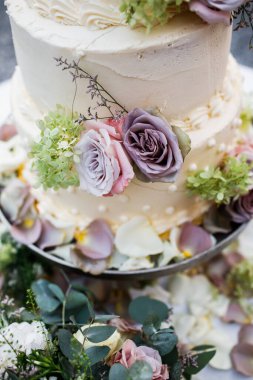 Düğün pastası dışarıda. Bir sürü çiçek. Yeşilliğin arka planında.