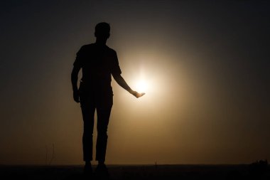 Günbatımının arka planında bir adamın silueti. Çeşitli figürler yapıyor..