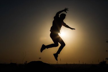 Günbatımının arka planında bir adamın silueti. Çeşitli figürler yapıyor..