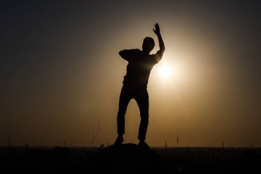 Günbatımının arka planında bir adamın silueti. Çeşitli figürler yapıyor..