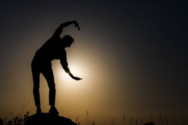 Günbatımının arka planında bir adamın silueti. Çeşitli figürler yapıyor..