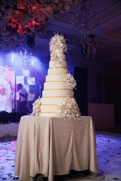 放在桌上的结婚蛋糕 在花的周围室内 — 图库照片
