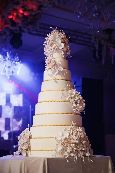 Wedding cake standing on the table. Around the flowers. Indoor.