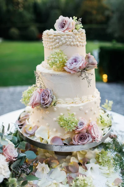放在桌上的结婚蛋糕 在花的周围外面 — 图库照片