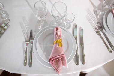 Tabaklar, çatallar, bardaklar ve bıçaklarla süslenmiş ahşap bir masada servis edilir.