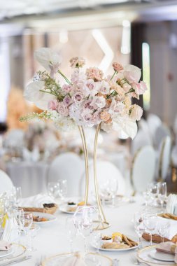 Misafirlerin masasında bir buket çiçek. Çok güzel dekore edilmiş bir düğün yeri resmi.