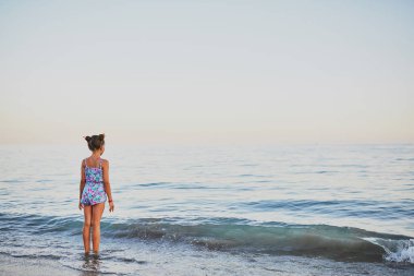 Kız sahil boyunca yürür. Gün batımı. Suda durup ufku seyrediyorum..
