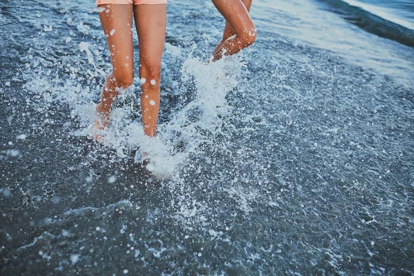 Kızlar denizin kenarında dururlar. Gün batımı.