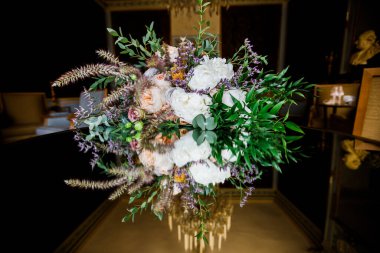 Gelinin düğün buketi. Masanın ayna yüzeyinde. Arka plandaki oda..