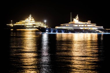 Geceleri suyun üzerinde duran iki tekne. Işıklarının ışığı suyu yansıtır..