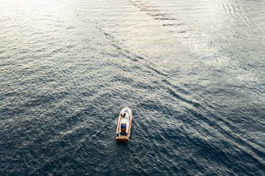 Gelinlikli bir çift kayalıklara yakın bir teknede oturuyor. Gün doğumu.