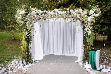 Tören alanı çiçekler, tüller ve mum dolu şişelerle süslenmiş..