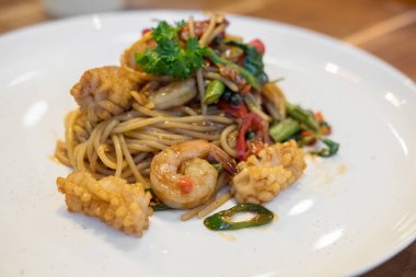 Beyaz tabakta Baharatlı deniz mahsulleri spagetti