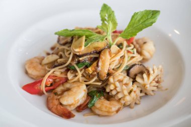 Beyaz tabakta Baharatlı deniz mahsulleri spagetti