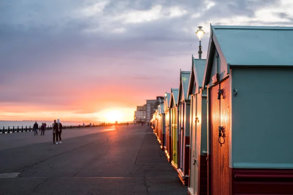 Cabanas de praia coloridas durante o pôr do sol em Brighton and Hove, Inglaterra — Fotografia de Stock