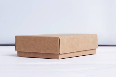 Karton kutu. Paket beyaz ahşap arka planda izole edilmiş. El işi kağıt kutu kenar görünümü. Küçük kare kapalı karton. Nakliye eko paketi. Teslimat paketi. Hediye fikri, eko-yaşam tarzı. Doğal konsept.