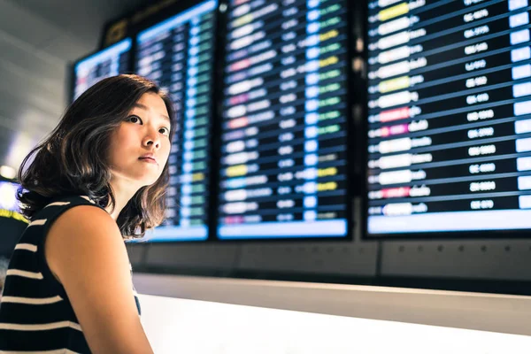 Vacker asiatisk kvinna resenären på informationsskärmen för flygning i en flygplats, resor eller tid koncept — Stockfoto