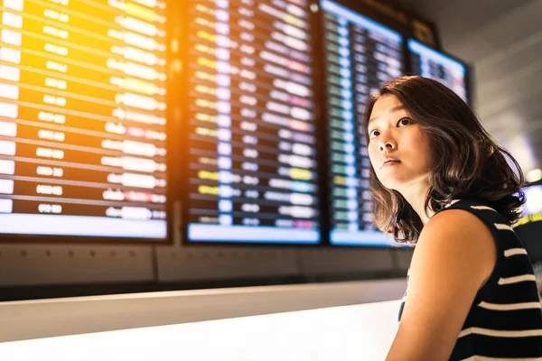 Vacker asiatisk kvinna resenären på informationsskärmen för flygning i en flygplats, resor eller tid koncept. varm ljus effekt — Stockfoto