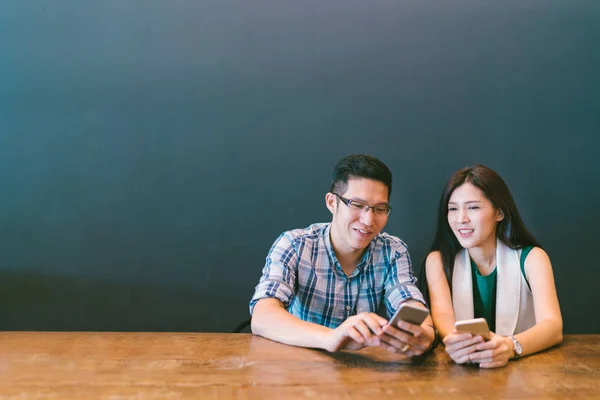 Joven pareja asiática o compañero de trabajo utilizando el teléfono inteligente en la cafetería, estilo de vida moderno con tecnología de gadget o concepto de negocio casual, con espacio para copiar —  Fotos de Stock