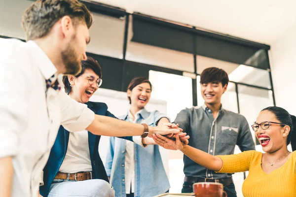 Diversos grupos multiétnicos de colegas felices unen sus manos. Equipo creativo, compañeros de trabajo ocasionales o estudiantes universitarios en una reunión de proyectos en una oficina moderna. Concepto de inicio o trabajo en equipo — Foto de Stock