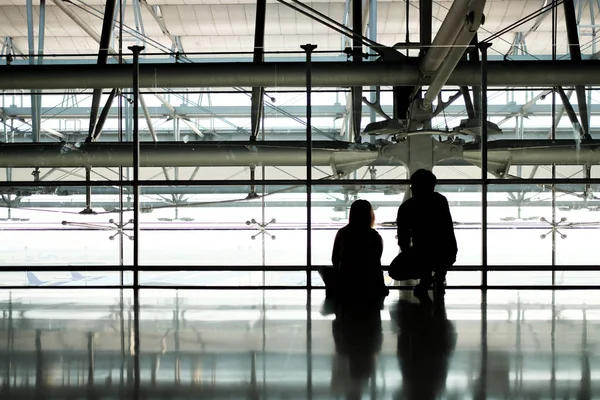 Σιλουέτα του άνδρα και της γυναίκας ταξιδιώτες περιμένει αεροπλάνο στο διάδρομο του αεροδρομίου — Φωτογραφία Αρχείου