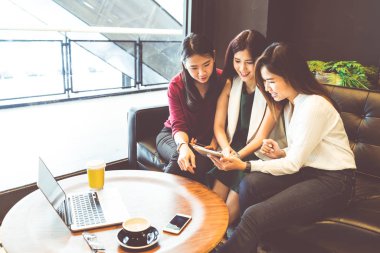 Divan Cafe, gadget teknolojisi veya geçici iş kavramı üzerinde çalışan kadın modern yaşam tarzı sohbet smartphone ve dizüstü bilgisayar kullanarak üç güzel Asyalı kızlar