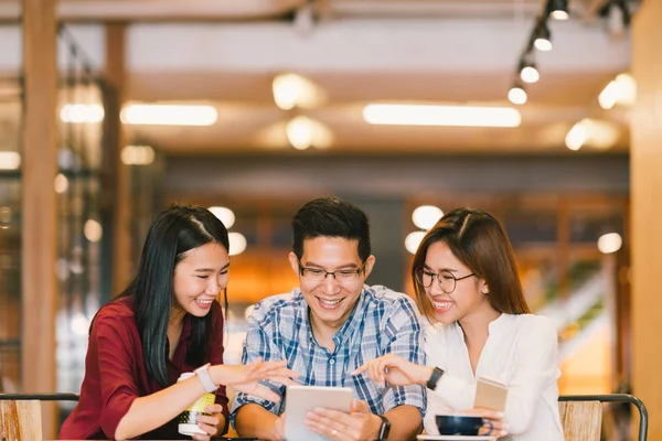 Unga asiatiska studenter eller medarbetare använder digitala tablett tillsammans på coffee shop, mångskiftande grupp. Affärer, frilansuppdrag på café, sociala möte eller utbildning koncept — Stockfoto