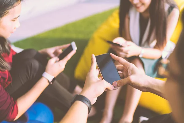 Group of three young people using smartphones together, modern lifestyle or communication technology gadget concept, depth of field effect — Stock Photo, Image