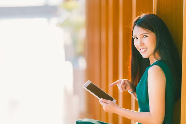 Asian businesswoman or college student using and pointing at digital tablet during sunset, at modern office or library. Business communication, gadget technology, or education concept with copy space — Stock Photo, Image