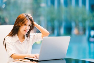 Asyalı kadın evde laptop ya da modern ofis ile çalışma. Ciddi, kafası karışır veya sinirli ifade. Kopya alanı ile.