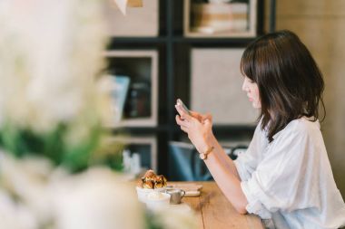 Güzel Asyalı kız Cafe'de çikolatalı tost, dondurma ve süt şurubu ile Smartphone kullanarak. Kahve Dükkanı tatlı ve modern rahat yaşam tarzı ya da cep telefonu teknoloji kavramı. Kopya alanı ile