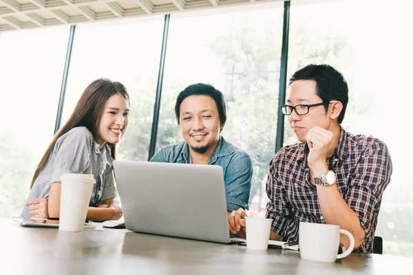 Grupo de jóvenes colegas de negocios asiáticos o estudiantes universitarios que utilizan la computadora portátil en la discusión informal del equipo, la reunión del proyecto de inicio o el concepto de tormenta de ideas de trabajo en equipo feliz, en la cafetería o la oficina moderna — Foto de Stock