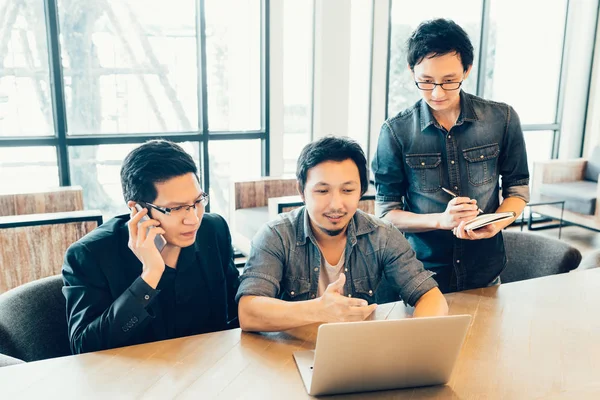 Tre unga asiatiska kolleger eller högskolestudenter i allvarlig affär möte eller team diskussion brainstorming, start projektpresentation eller teamwork koncept, på kafé eller moderna kontor — Stockfoto