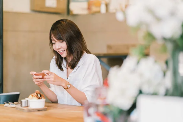 Beautiful Asian girl taking photo of sweet desserts at coffee shop, using smartphone camera, posting on social media. Food photograph hobby, casual relax lifestyle, modern social network habit concept — Stock Photo, Image