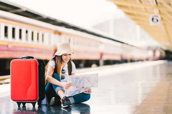 Asiatiska ryggsäck resenären kvinna använder generiska lokal karta, lokalisering ensam på tåget stationen plattform med bagage. Sommar och semester resor eller ung turist koncept — Stockfoto