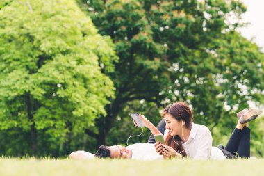 Genç Asyalı güzel çift veya üniversite öğrencileri ile birlikte bahçede müzik dinlemek alanı kopyalayın. Boş zaman etkinliği, düğün veya rahat yaşam tarzı kavramı rahatlatıcı aşk ilişkisi,