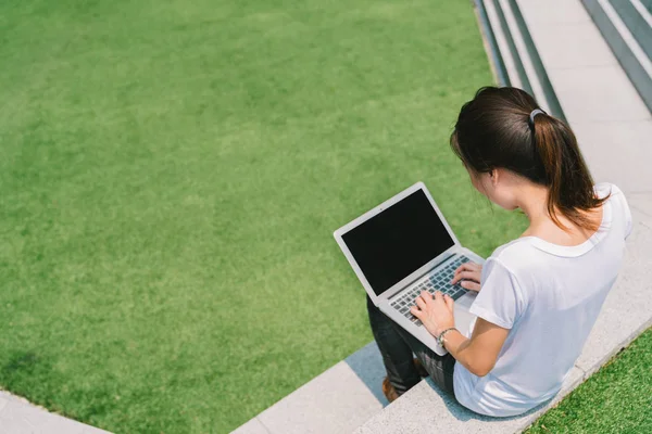 Azjatycka college student lub freelance kobieta za pomocą laptopa na schodach w kampusie Uniwersytetu lub nowoczesny park. Informacje o technologii, edukacji lub dorywczo biznes koncepcja. Miejsce na zielonej trawie stoczni — Zdjęcie stockowe