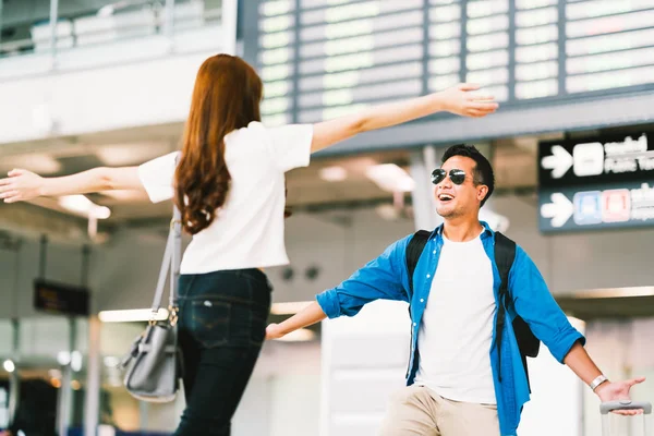 Asiatisk tjej plocka upp sin pojkvän på flygplatsen ankomst gate, välkomnar tillbaka hem från studera eller arbeta utomlands. Unga par kärlek och kram, smekmånad, eller reser koncept — Stockfoto