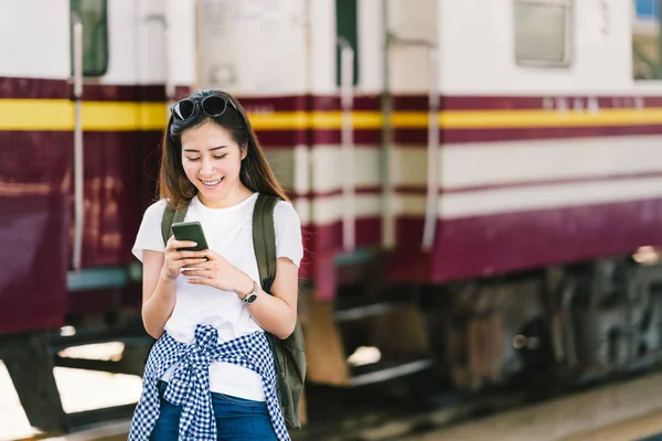 Ασιατισα θηλυκό ταξιδιώτη, όμορφη γυναίκα χρήση χάρτη ή κοινωνικών μέσων μαζικής ενημέρωσης check-in στο smartphone σε πλατφόρμα σιδηροδρομικό σταθμό τραίνων. Μικρά τουριστικά περιπέτεια, τουρισμός Ασία, καλοκαιρινές διακοπές σιδηροδρομικά ταξίδια έννοια — Φωτογραφία Αρχείου