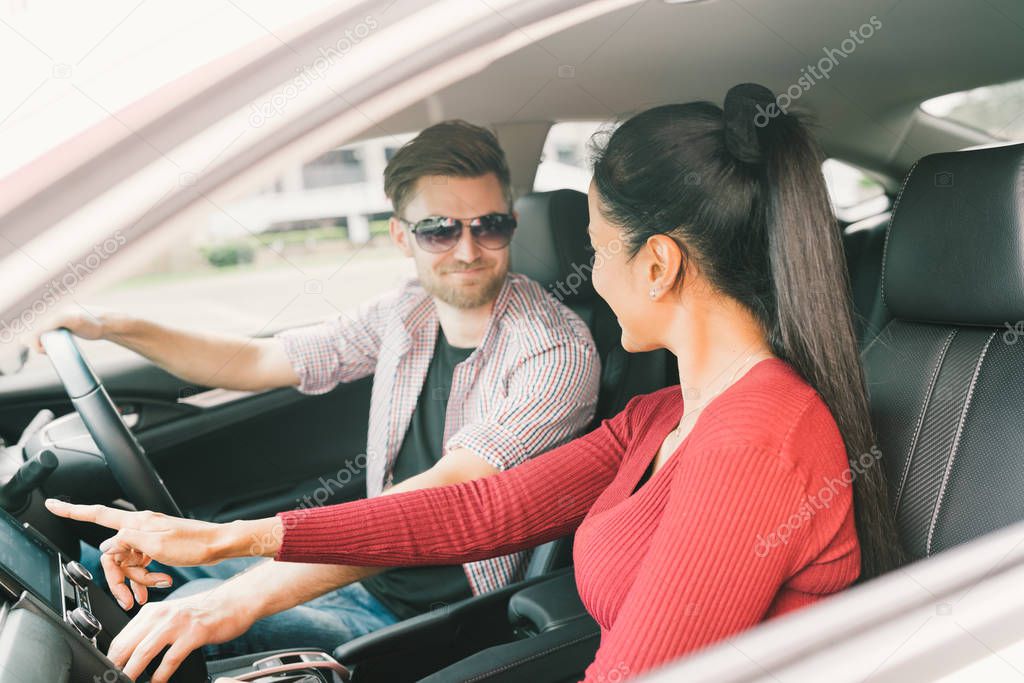 Multiethnic lover couple traveling together by car, using radio screen or GPS navigation system. Love or transportation technology concept