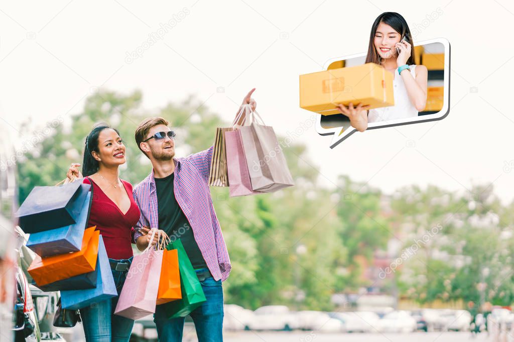 Happy Multi-ethnic couple with shopping bag, white man point young small business owner lady, sell goods on mobile phone call. E commerce, shopaholic modern lifestyle, or online shop marketing concept
