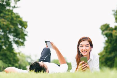 Müzik dinlemek cep telefonu genel Park, kopya alanı ile birlikte kullanarak Asya aşık çift veya üniversite öğrencisi. Eğlence Etkinlik, eğitim, aşk ilişkisi, evlilik veya rahat yaşam tarzı kavramı