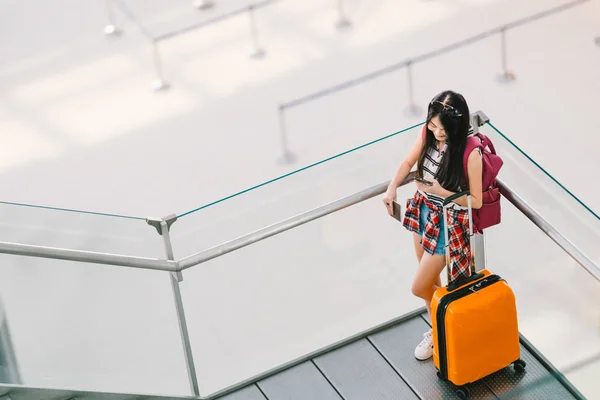 Söt teenage asiatiska resenär girl, collegestudent med smartphone samtal eller chatt på flygplatsen med bagage, ryggsäck. Web incheckning, lonely resor studie utomlands, eller internationella turism livsstilskoncept. — Stockfoto