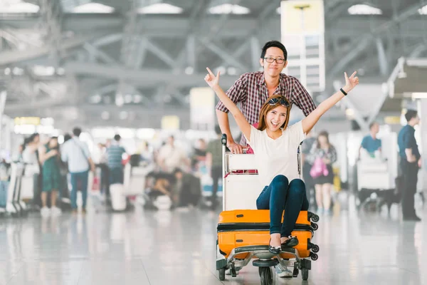 Unga asiatiska turist par glad och upprymd tillsammans för resan, Flickvän sitter och hejar på bagage vagn eller bagage vagn. Semester semester resor utomlands koncept, med kopia utrymme — Stockfoto