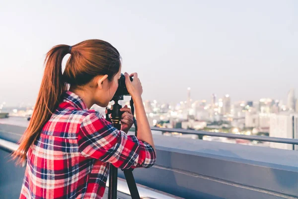 Cabelo longo mulher asiática tirar foto paisagem urbana na construção de telhado em situação de pouca luz. Fotografia ou conceito de hobby. Com espaço de cópia — Fotografia de Stock