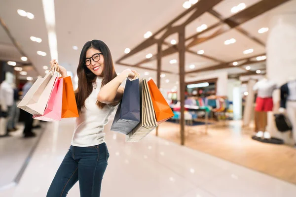 Fiatal aranyos ázsiai nő gazdaság bevásárló táskák, és mosolyogni boldogan, áruház és bevásárló központ életlenítés háttér-val másol hely. Shopaholic, eladásösztönzés esemény, vagy a modern életmód fogalma — Stock Fotó