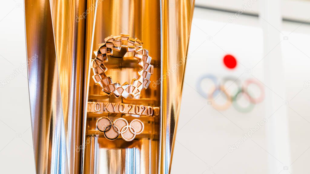 Tokyo, Japan - Nov 1, 2019: Gold trophy cup of Tokyo Summer Olympic 2020 show in Japan Olympic Museum, Olympic games logo in background. International sport event, or tournament host country concept