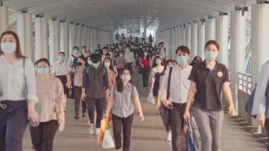 Bangkok, Tayland - 7 Nisan 2020: Kalabalık Asyalılar yaya yolunda yürürken maske takıyor. Coronavirus hastalığı Covid-19 salgını, şehir hayatı veya hava kirliliği konsepti. 4K ağır çekim