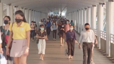 Bangkok, Tayland - 7 Nisan 2020: Kalabalık Asyalılar yaya geçidinde yüz maskesi takıyor, sabah trafiği. Coronavirus hastalığı Covid-19 salgını, şehir hayatı veya hava kirliliği konsepti